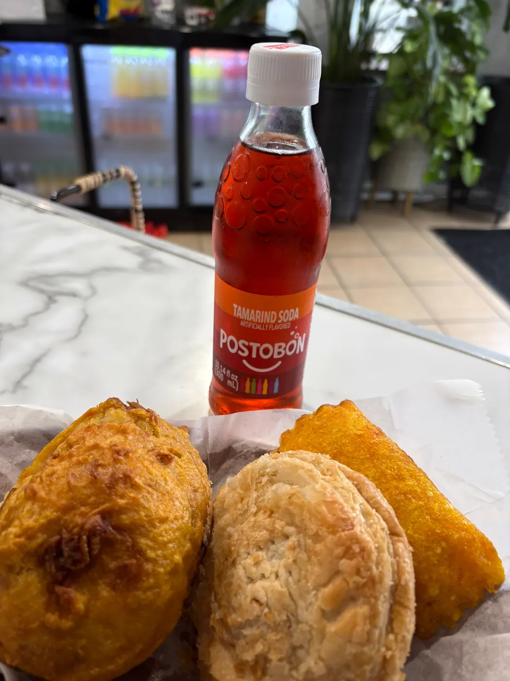 Empanadas, a baked treat, and a bottled Colombian soda on the cafe counter