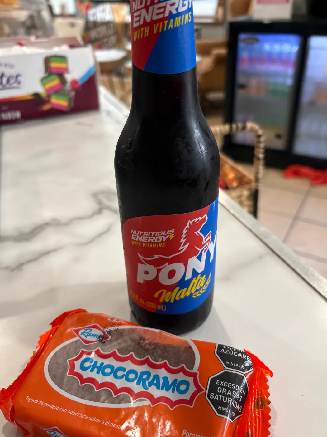 A bottled malt drink and packaged chocolate cake at the cafe
